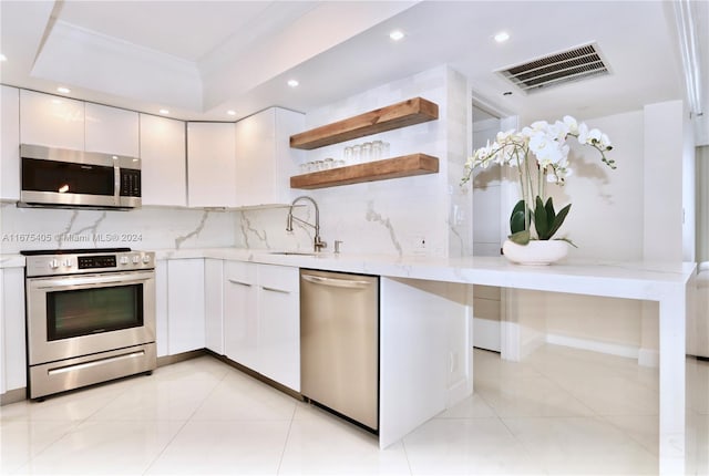 kitchen with ornamental molding, white cabinets, stainless steel appliances, and backsplash