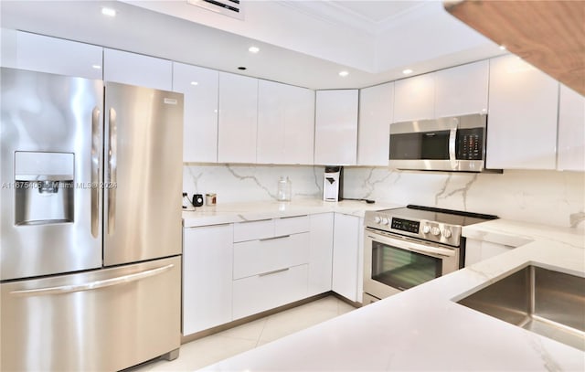 kitchen with light stone counters, stainless steel appliances, backsplash, and white cabinets