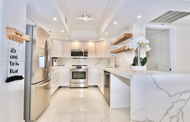 kitchen with sink, white cabinetry, stainless steel appliances, light stone counters, and decorative backsplash