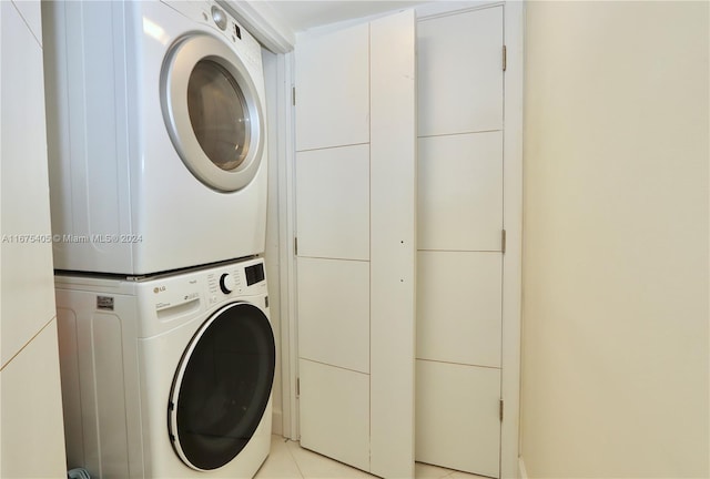 laundry area featuring stacked washer / drying machine and light tile patterned flooring