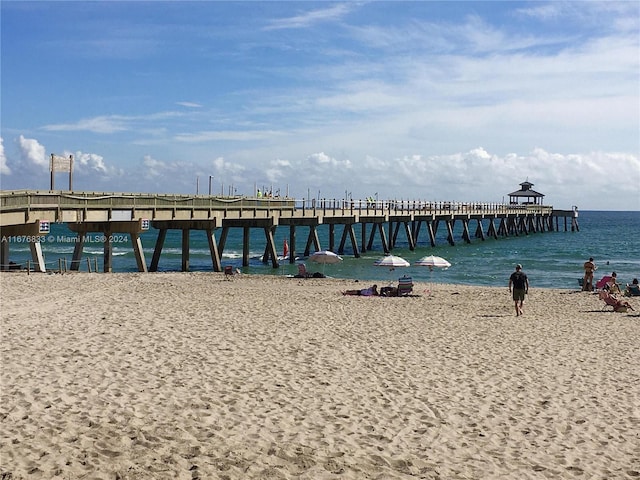 view of dock featuring a water view and a beach view