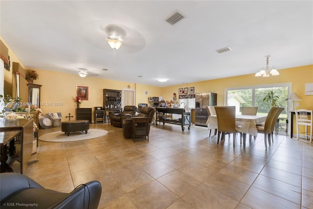 living room featuring light tile patterned flooring and ceiling fan with notable chandelier