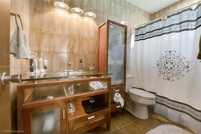 bathroom with tile walls, vanity, toilet, and tile patterned floors