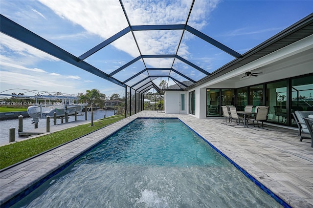 view of pool with ceiling fan, a boat dock, a water view, glass enclosure, and a patio