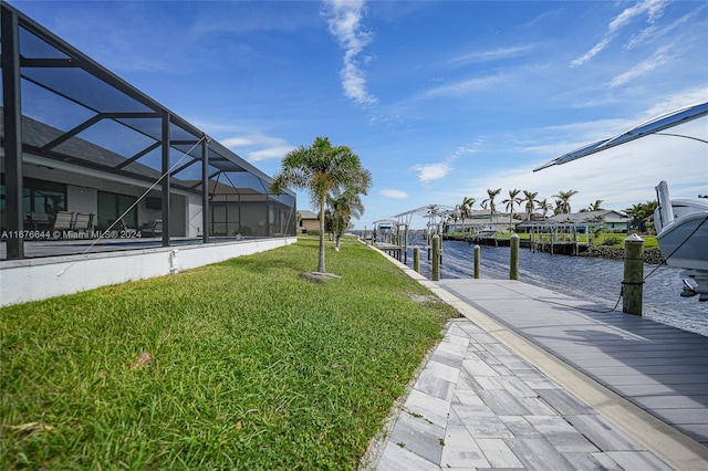 dock area with a lanai, a water view, and a yard