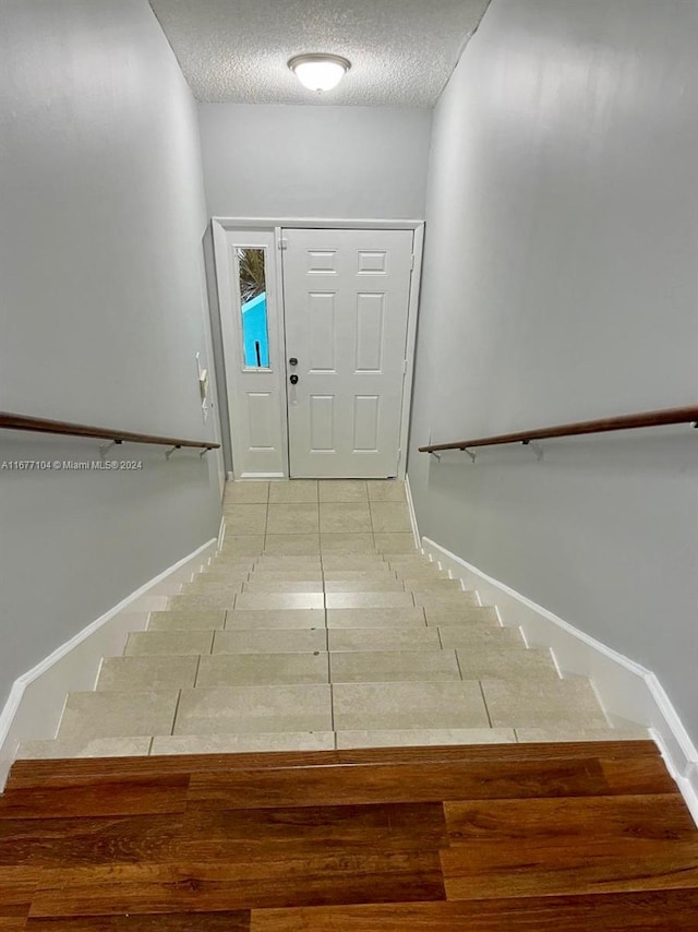 stairway featuring a textured ceiling and tile patterned flooring