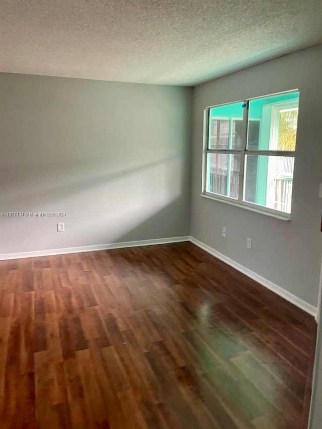 empty room with a textured ceiling and dark hardwood / wood-style floors