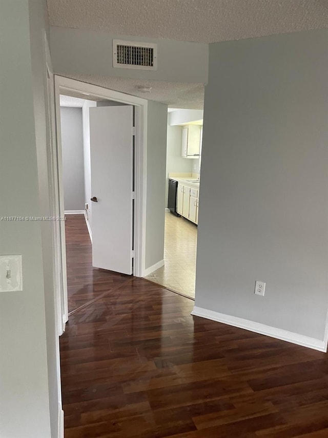 hall featuring a textured ceiling and dark hardwood / wood-style flooring