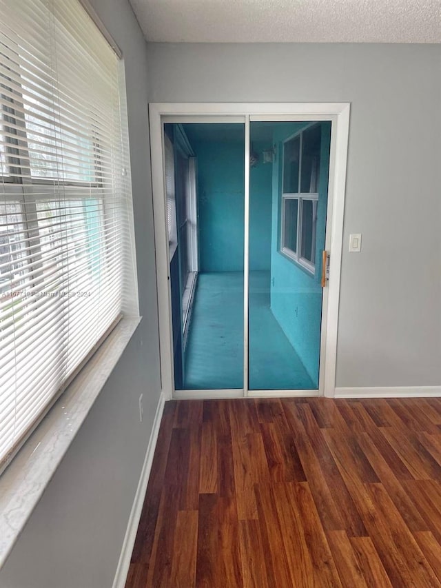 unfurnished room with dark hardwood / wood-style floors and a textured ceiling