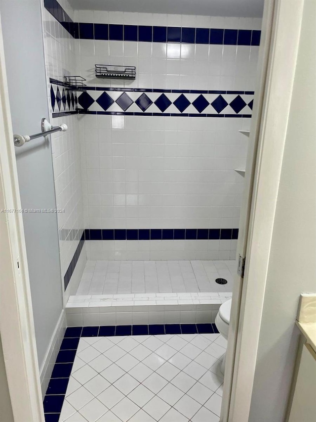 bathroom featuring vanity, toilet, tiled shower, and tile patterned flooring