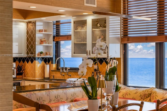 kitchen with decorative backsplash, a water view, a wealth of natural light, and sink