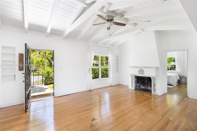 unfurnished living room with built in features, a large fireplace, baseboards, and light wood-style floors