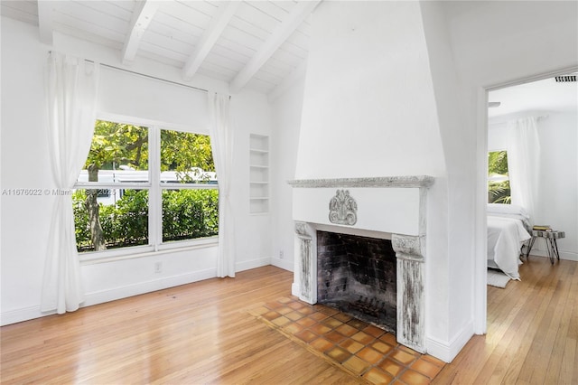 living room featuring built in features, light wood-style floors, a fireplace, and plenty of natural light