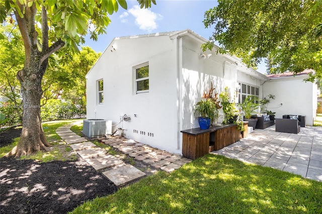 view of side of home featuring a patio, central AC unit, an outdoor living space, crawl space, and stucco siding