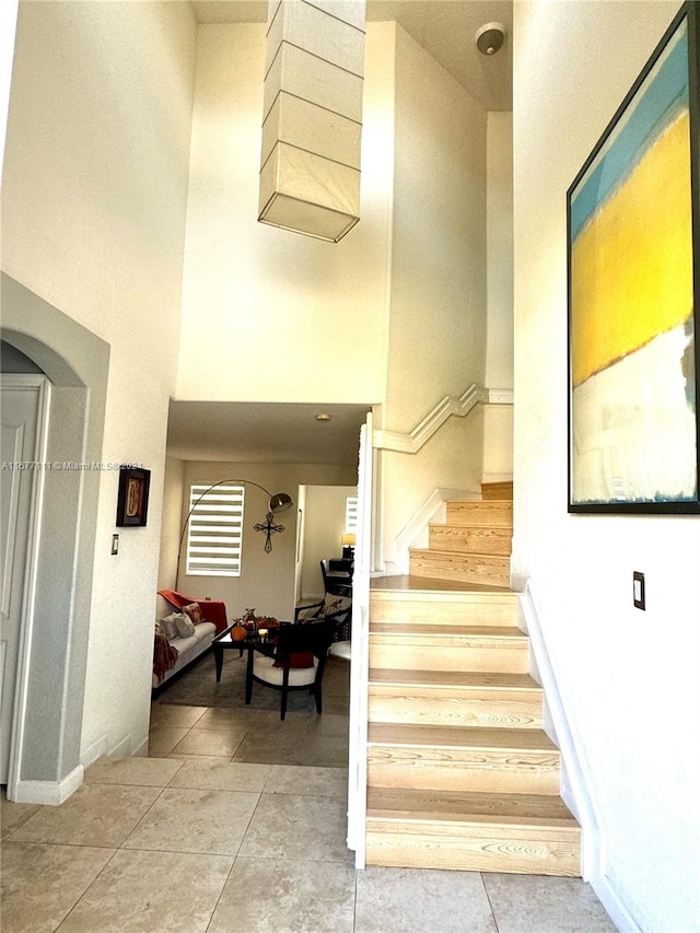 stairs featuring a towering ceiling and tile patterned flooring