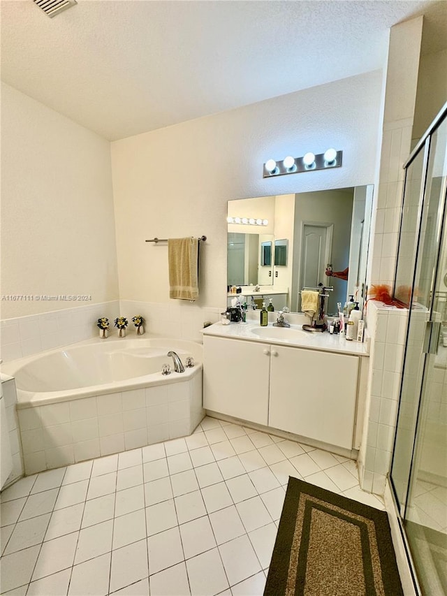 bathroom featuring vanity, plus walk in shower, a textured ceiling, and tile patterned flooring