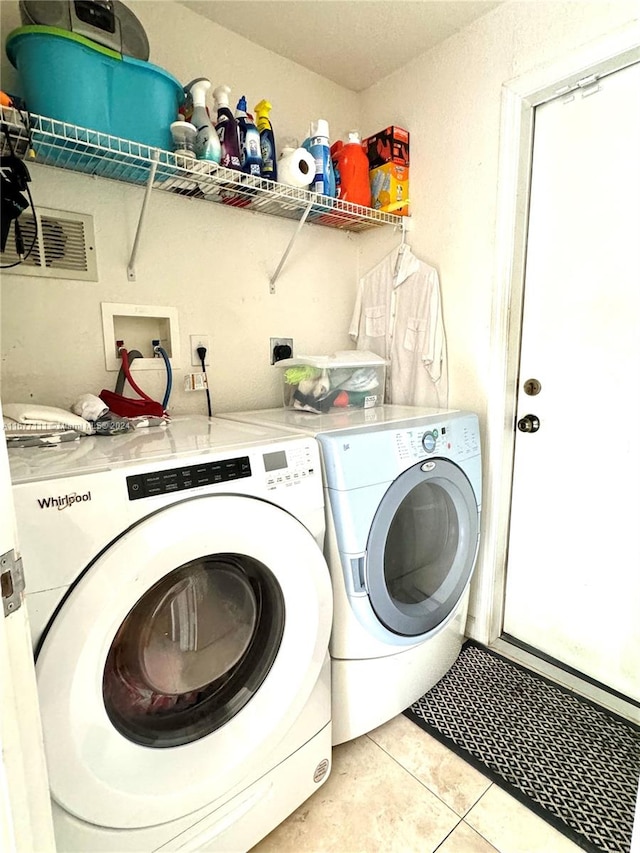 clothes washing area with light tile patterned flooring and washing machine and clothes dryer