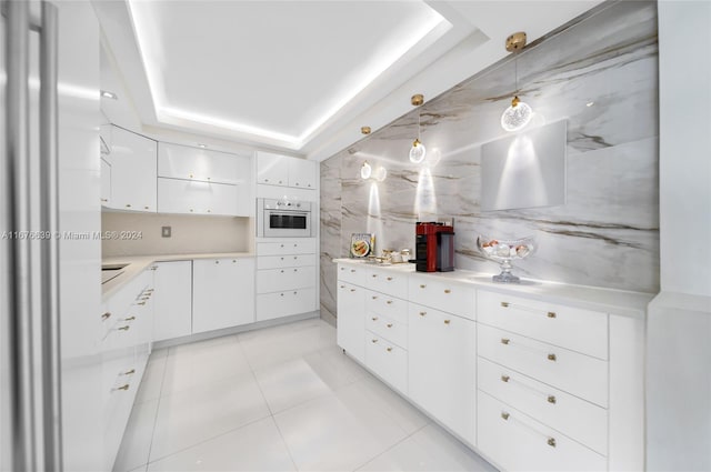 kitchen with oven, white cabinets, a raised ceiling, light tile patterned flooring, and pendant lighting