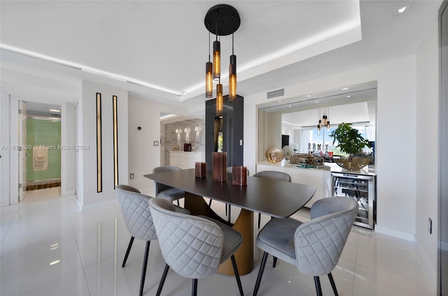 dining room with wine cooler, a raised ceiling, and light tile patterned floors