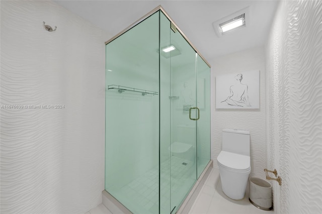 bathroom featuring a shower with door, toilet, and tile patterned flooring