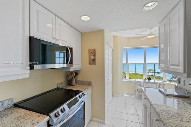 kitchen with white cabinetry, stainless steel appliances, a textured ceiling, and a water view