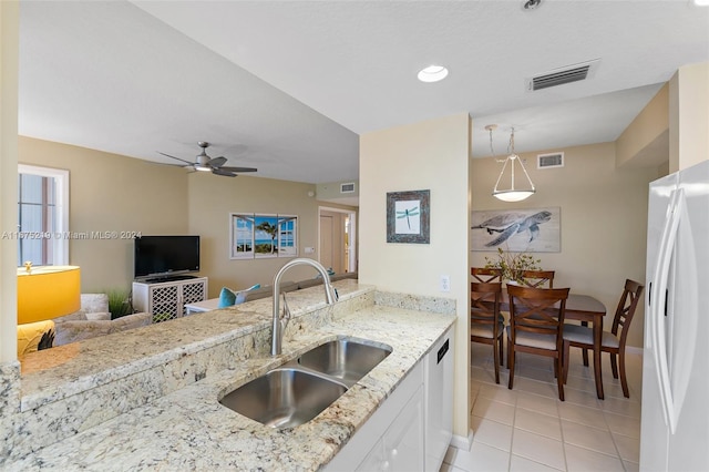 kitchen with white cabinets, light stone counters, white fridge with ice dispenser, decorative light fixtures, and sink