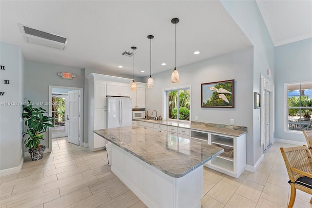 kitchen featuring a kitchen island, white cabinetry, white appliances, and plenty of natural light