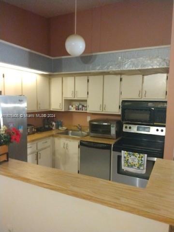 kitchen featuring cream cabinetry, sink, appliances with stainless steel finishes, and decorative light fixtures