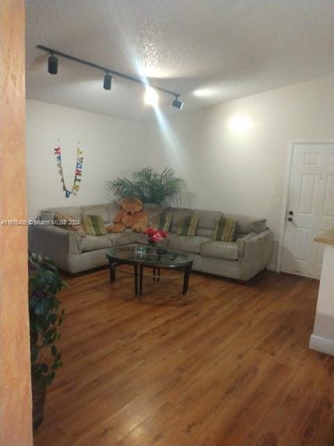 living room featuring a textured ceiling, dark hardwood / wood-style floors, and rail lighting