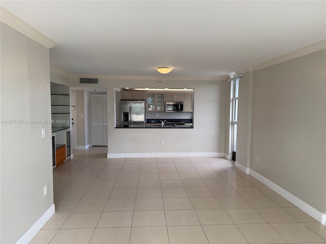 unfurnished living room with crown molding, sink, and light tile patterned floors