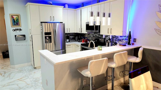 kitchen with kitchen peninsula, stainless steel appliances, a breakfast bar, pendant lighting, and white cabinetry