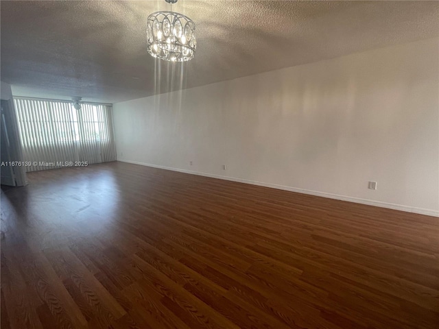 unfurnished room with dark hardwood / wood-style floors, a textured ceiling, and a chandelier