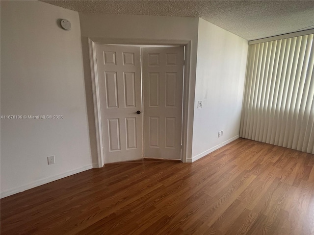 empty room with a textured ceiling and light hardwood / wood-style flooring