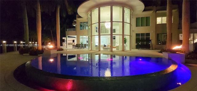 pool at twilight featuring a patio area and a hot tub