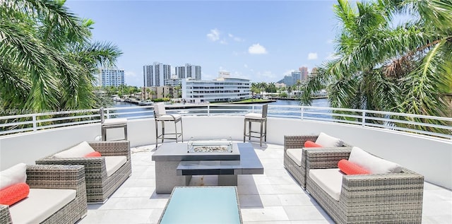 view of patio / terrace featuring a balcony, a water view, and an outdoor living space with a fire pit