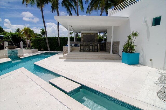 view of pool with a hot tub, a bar, and a patio