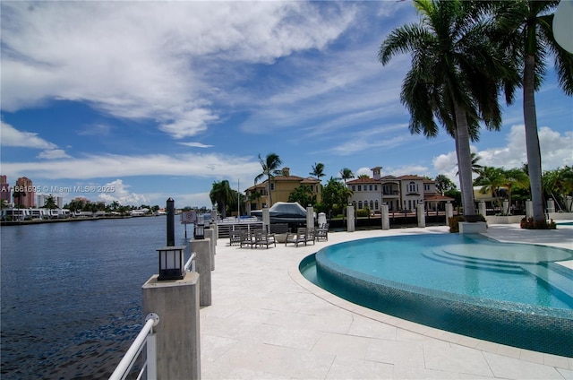 view of pool featuring a water view and a patio