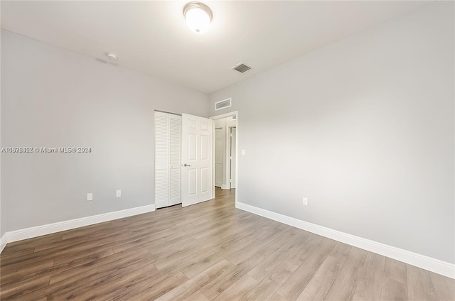 unfurnished bedroom with light hardwood / wood-style flooring and a closet