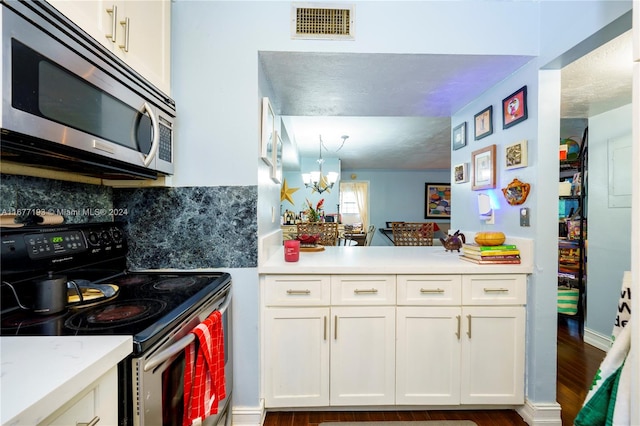 kitchen featuring appliances with stainless steel finishes, white cabinetry, a chandelier, and dark wood-type flooring