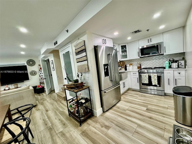 kitchen with white cabinets, stainless steel appliances, and tasteful backsplash