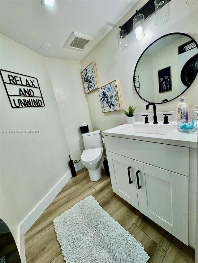 bathroom featuring vanity, wood-type flooring, and toilet