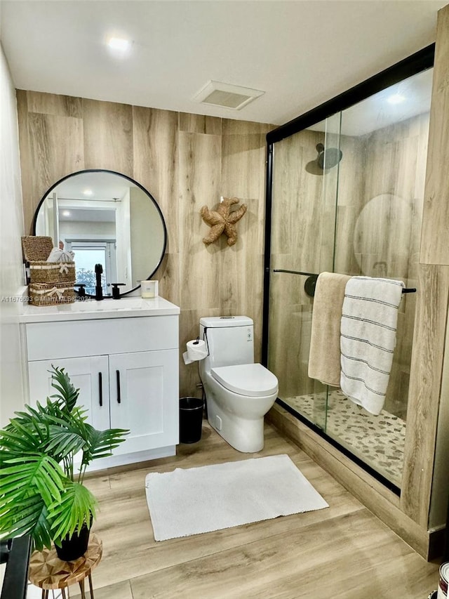 bathroom featuring hardwood / wood-style flooring, toilet, vanity, an enclosed shower, and wood walls