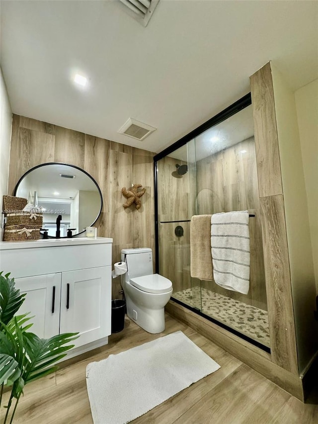 bathroom featuring an enclosed shower, wood walls, toilet, vanity, and hardwood / wood-style floors