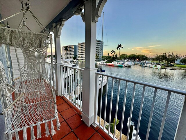 balcony at dusk featuring a water view