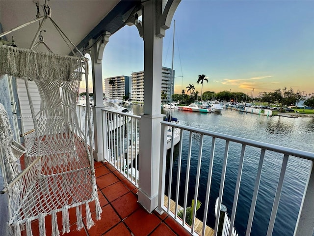 balcony at dusk featuring a water view