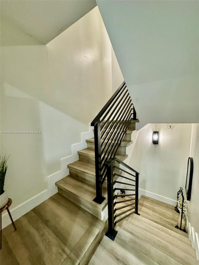 stairway featuring hardwood / wood-style flooring and vaulted ceiling