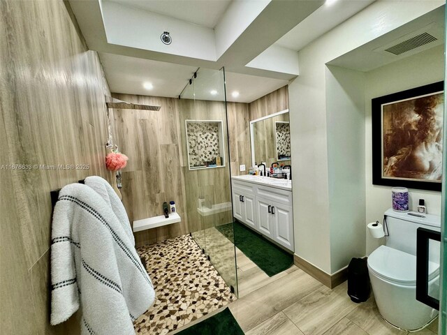 bathroom with toilet, hardwood / wood-style floors, vanity, and tiled shower