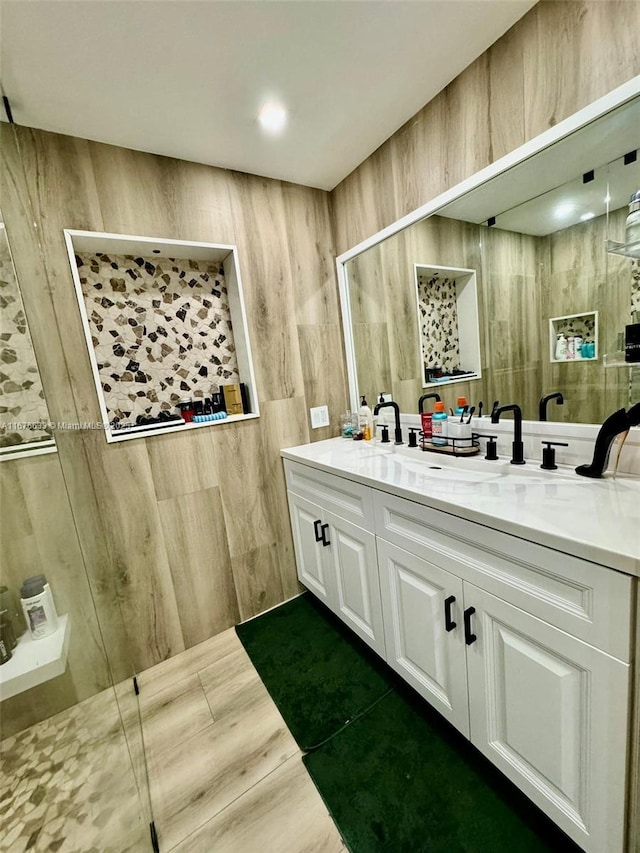 bathroom with tile walls, vanity, and walk in shower