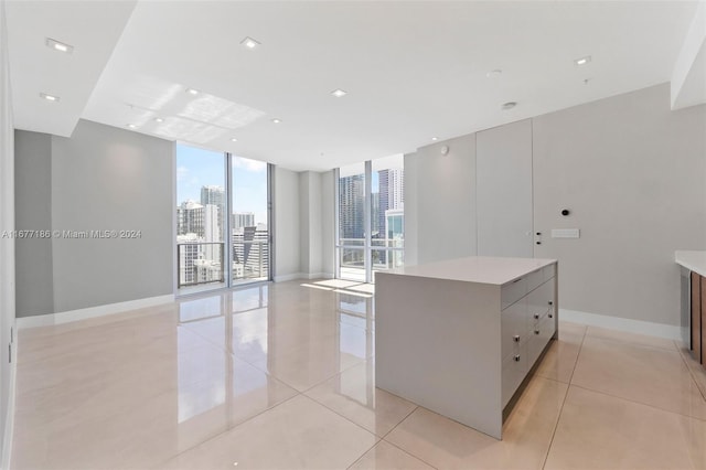 interior space with a large island, a wall of windows, light tile patterned flooring, and gray cabinetry