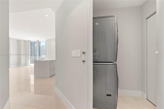 hall featuring light tile patterned flooring and stacked washer and clothes dryer